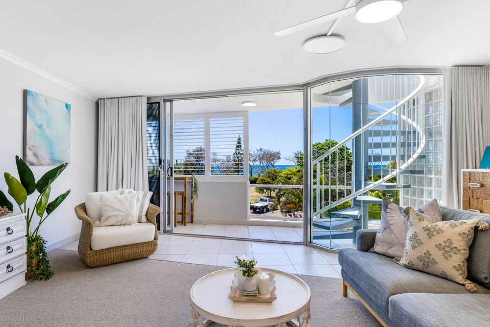 Light-filled apartment living room with a spiral staircase and balcony doors