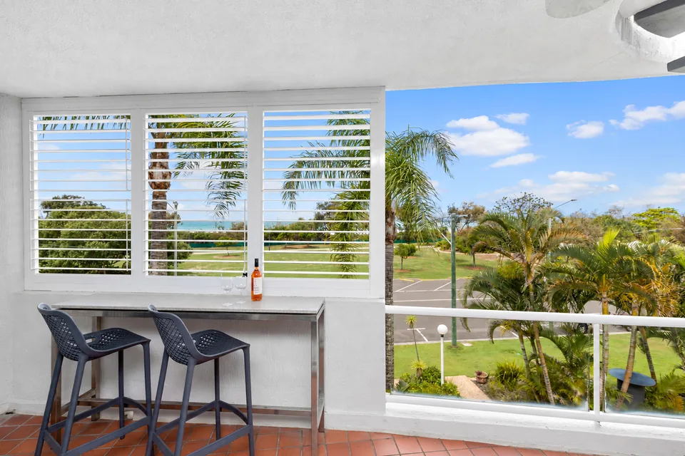 Apartment balcony seating looking out to palms and the coast