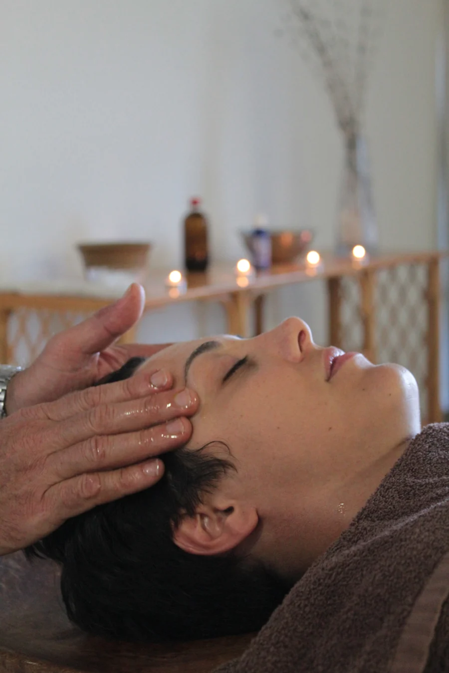 Hands gently working around the temples during a head massage