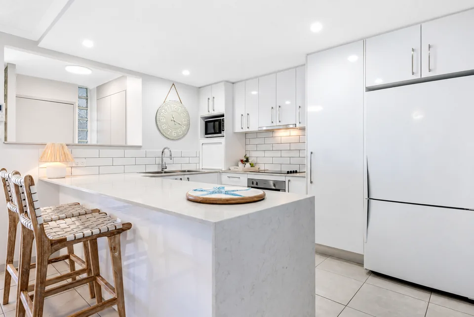 A full apartment kitchen with stone benchtop and breakfast stools